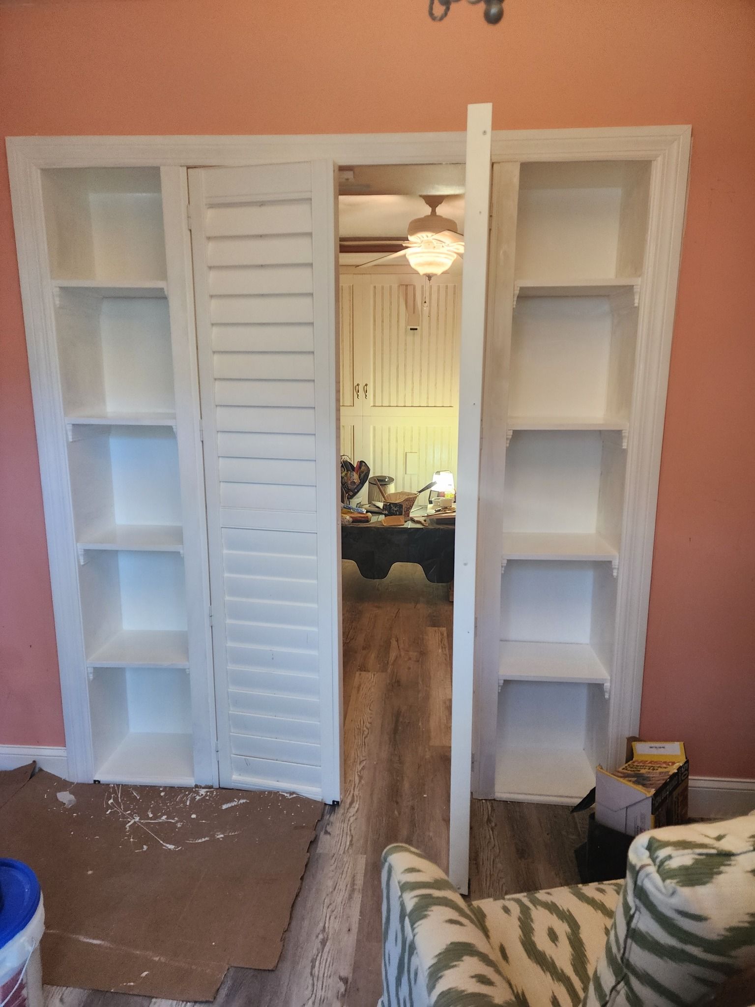 White shelving units flank a doorway, with shutter-style doors. Interior view.