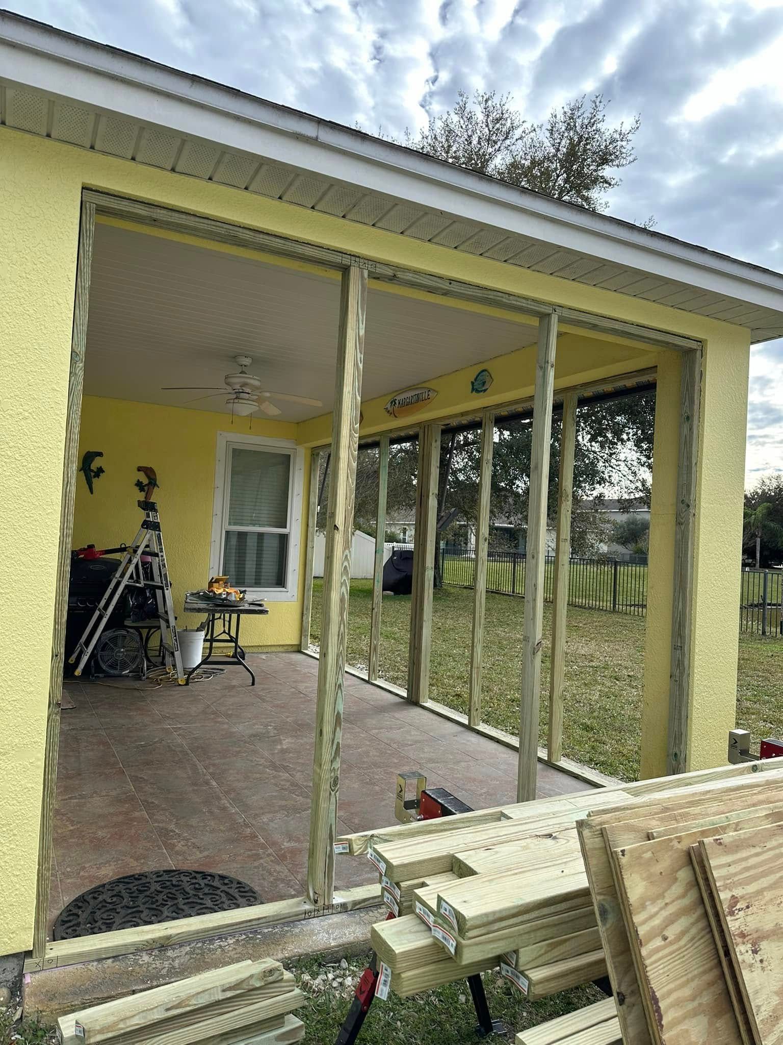 Construction site with yellow building and wood framing. Openings for sliding doors or windows.