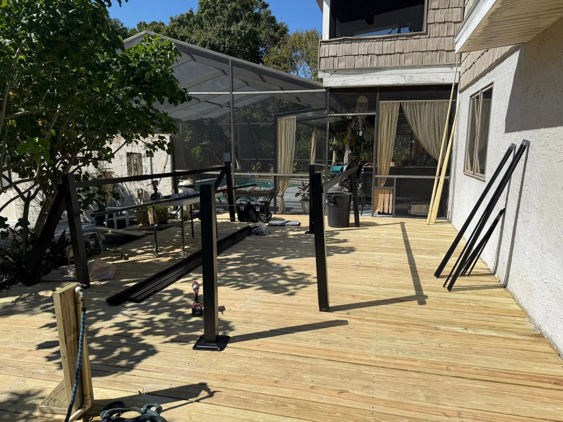 Wooden deck with black railing under construction. Includes a screened porch and building.