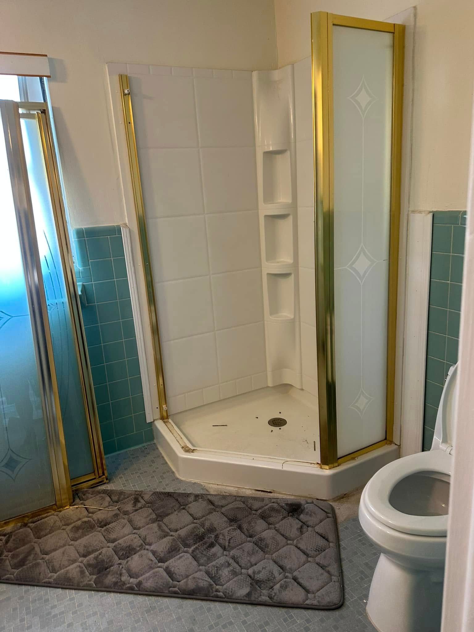 Bathroom with a white and gold framed shower, toilet, and blue tile walls.