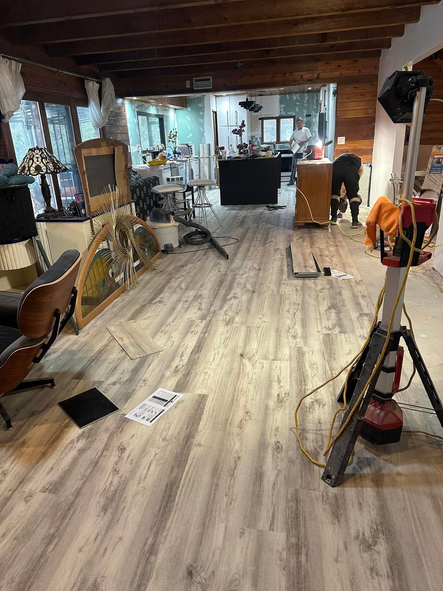 Interior view of a workshop with wooden floors and various objects, including a tall light and furniture.
