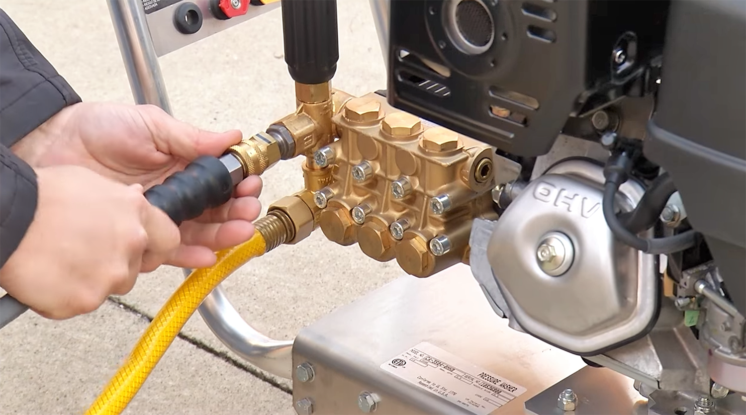 Plumbing pipes and fixtures surrounded by spray foam in a corner during construction, with red paint and a built-in niche.