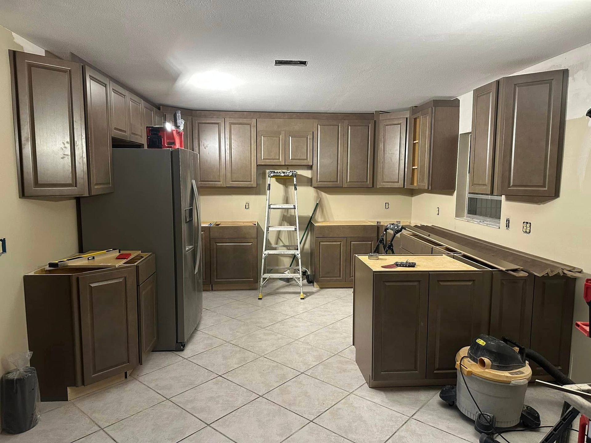 Kitchen renovation with brown cabinets, a refrigerator, and tools.