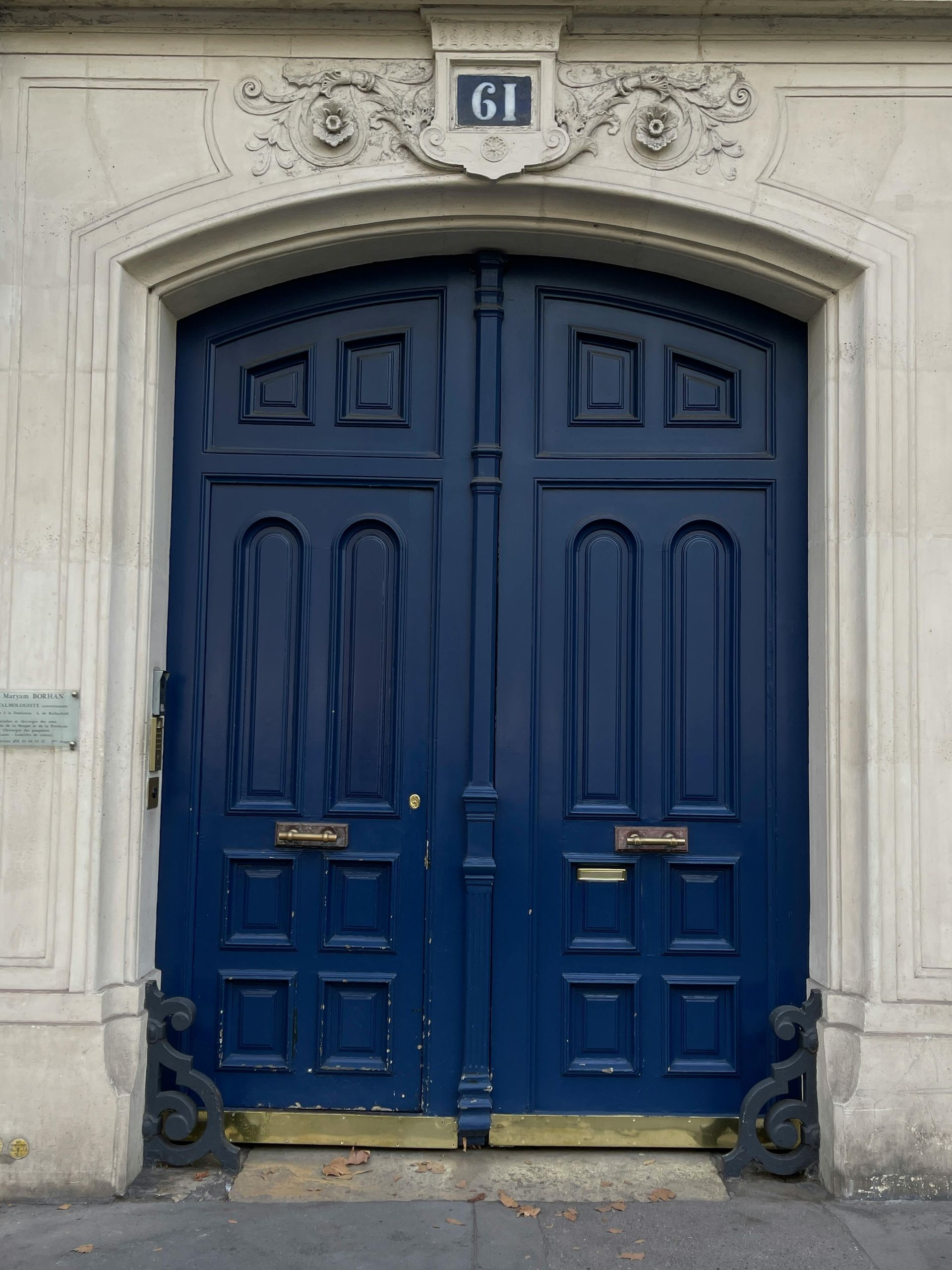 Blue double doors with number 61 above, set in a light stone doorway. Ornate detail.