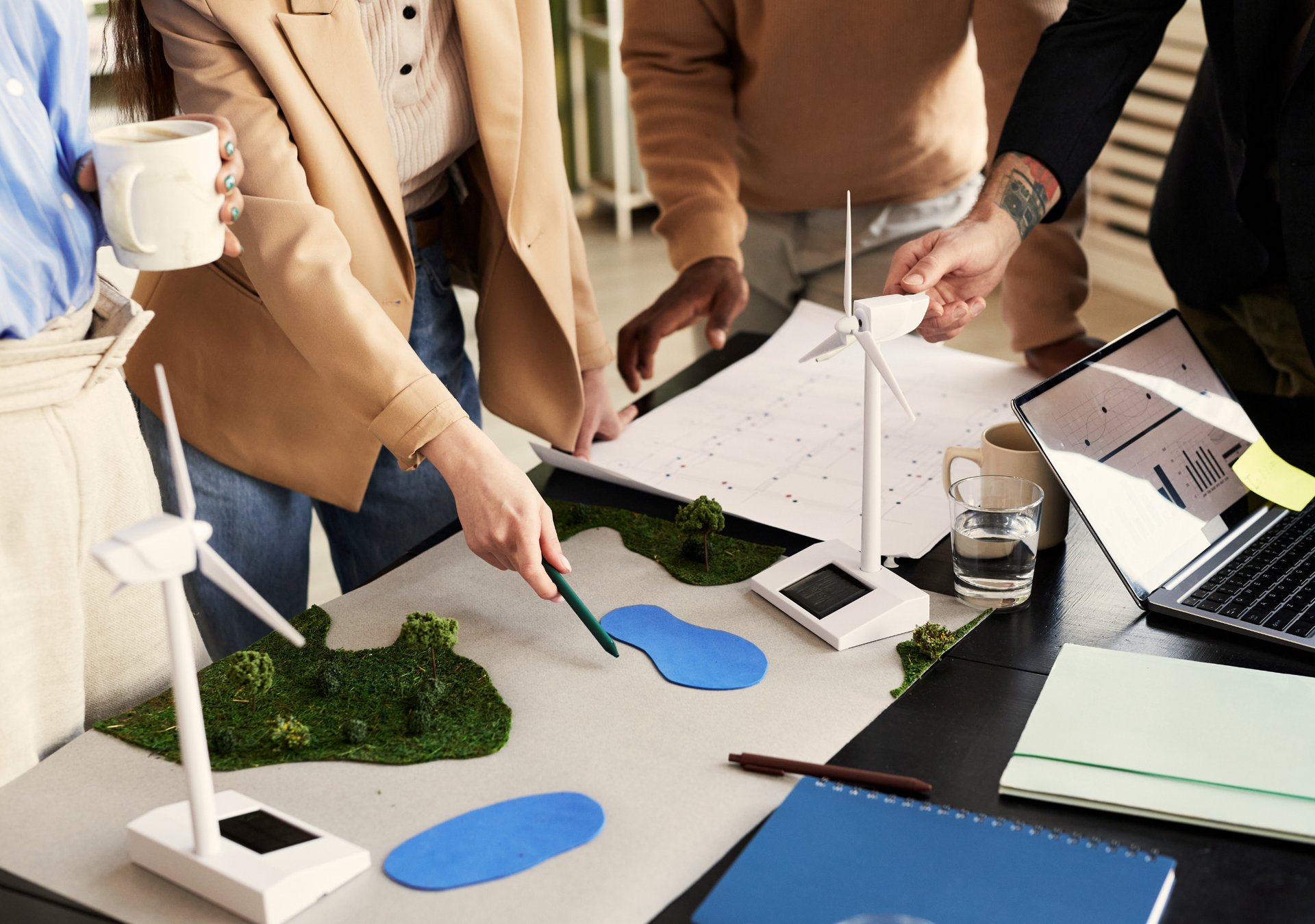 A group of people are looking at a model of a wind turbine on a table.