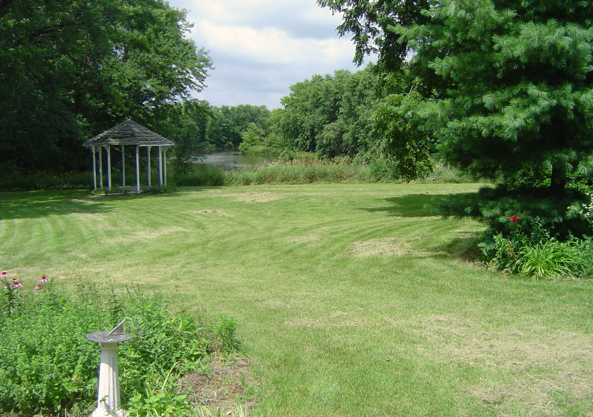 A gazebo in the middle of a lush green field.