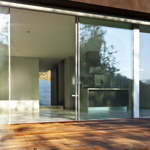 Sliding glass doors open to a modern kitchen with natural light and a wooden deck.