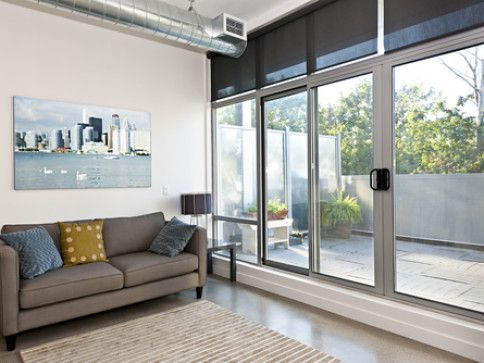 Modern living room with a couch, artwork, and large glass doors leading to a patio.