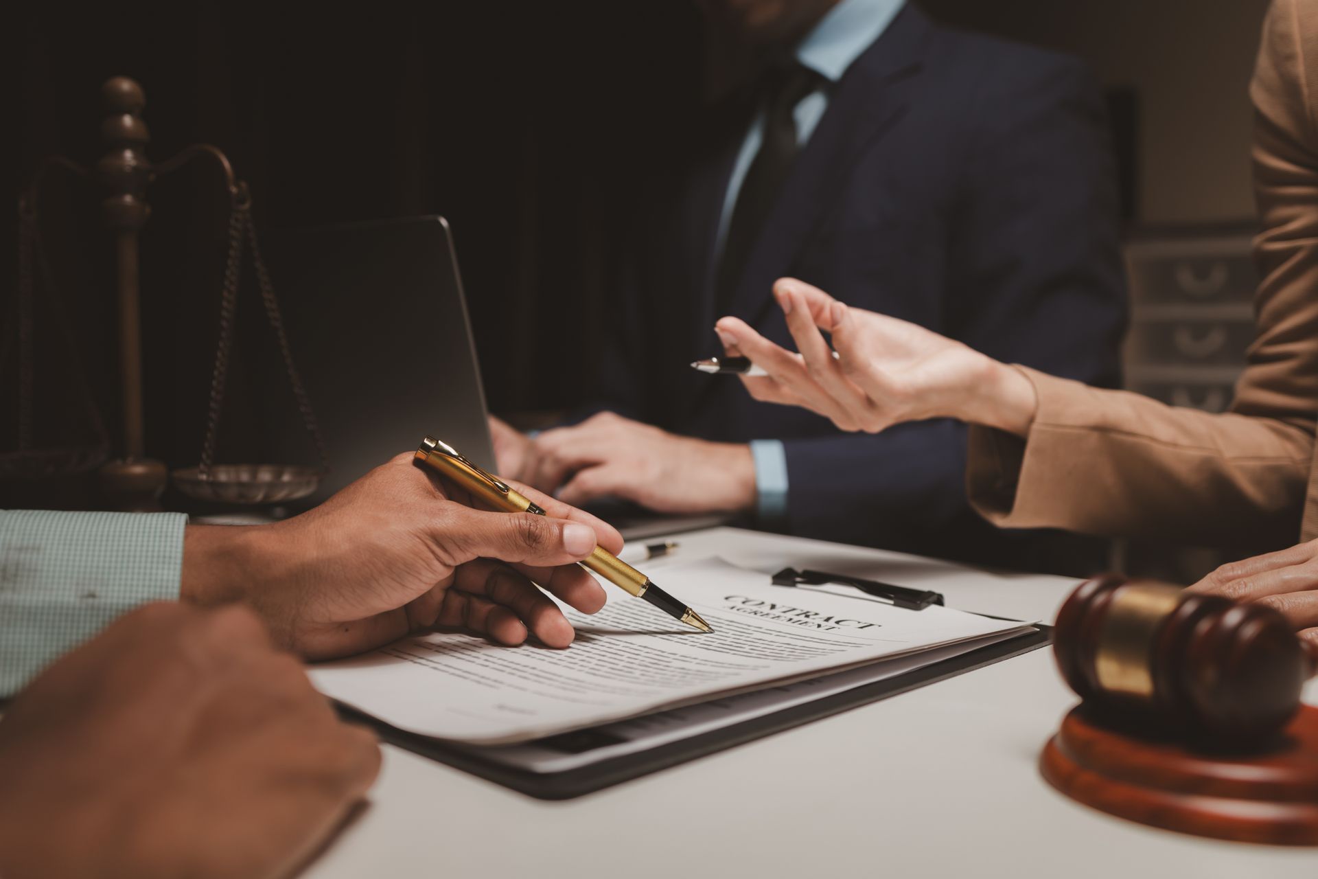 A group of people are sitting at a table with a laptop and a judge 's gavel.