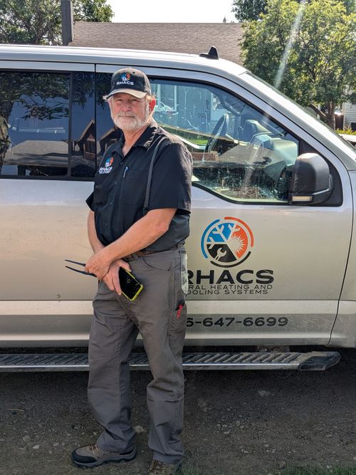 A young man standing in front of a van that says rhacs