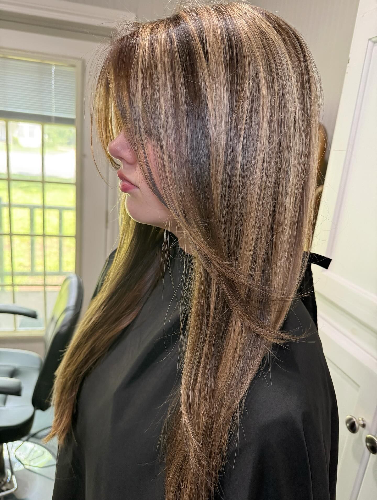 Woman with long, blonde hair; looking left, slightly smiling; against a gray background.