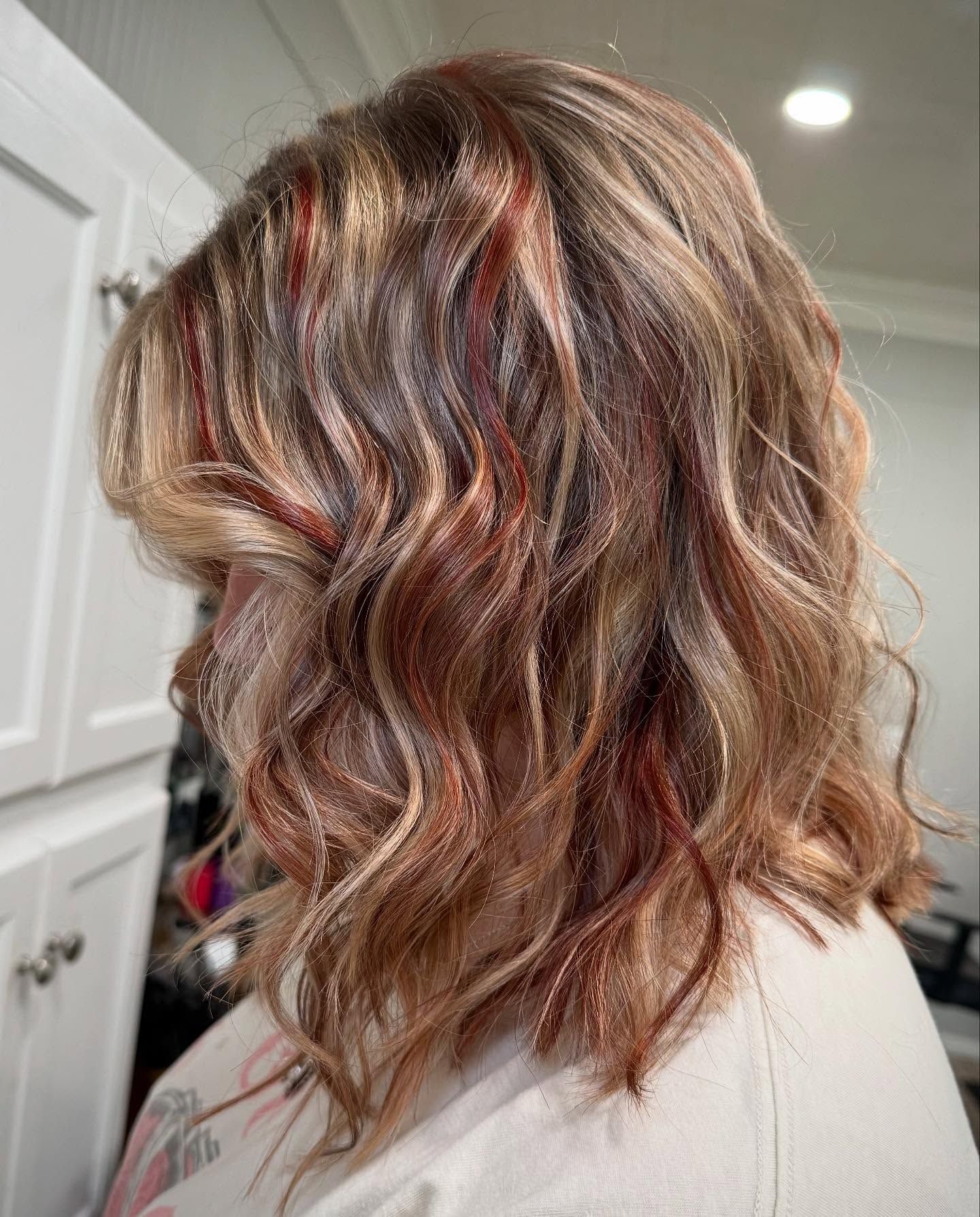 Hairdresser cutting a person's dark hair with scissors and a comb. They are wearing a salon cape.