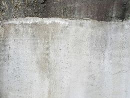 Gray concrete wall with dark upper section, possibly dirty or weathered.