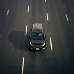 Dark car driving on a highway, viewed from directly above.