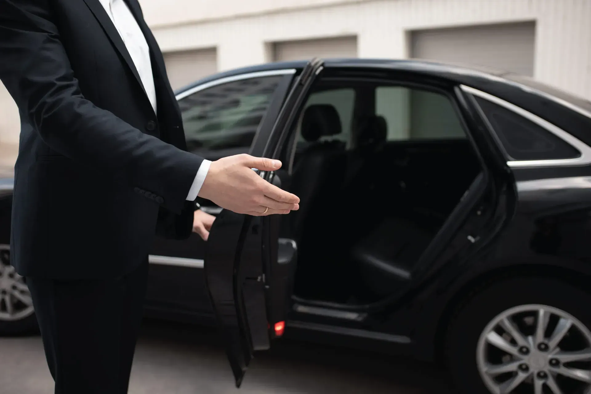 Man in suit opening car door.