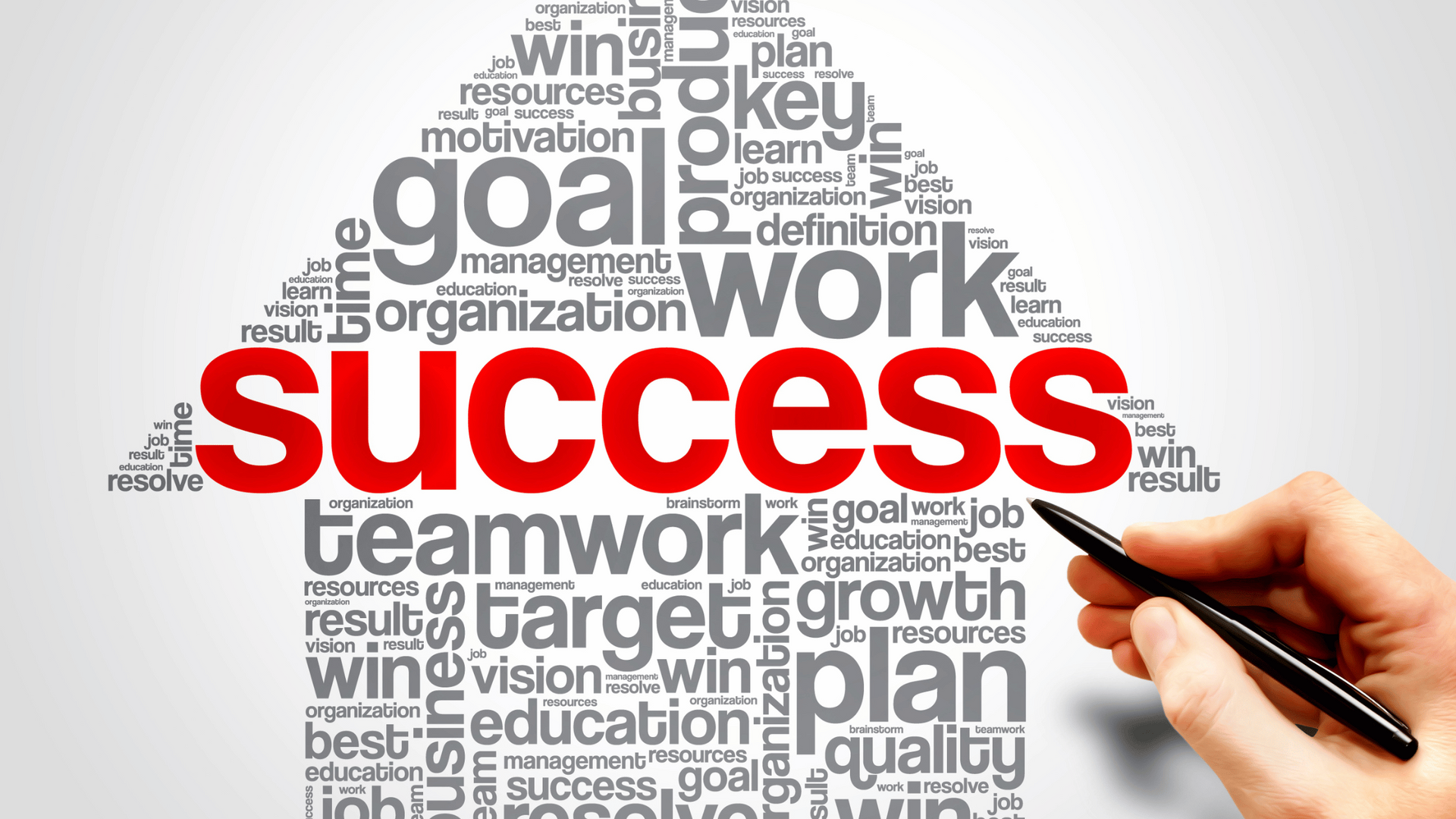 A hand is holding a pen in front of a word cloud that says success.