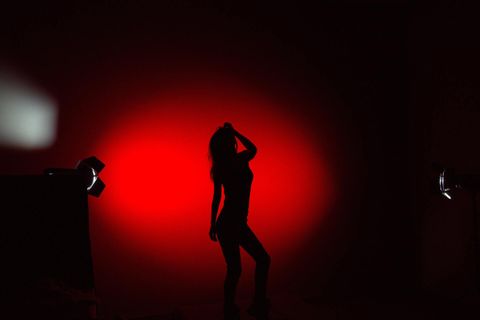 Silhouette of woman posing against red backdrop.