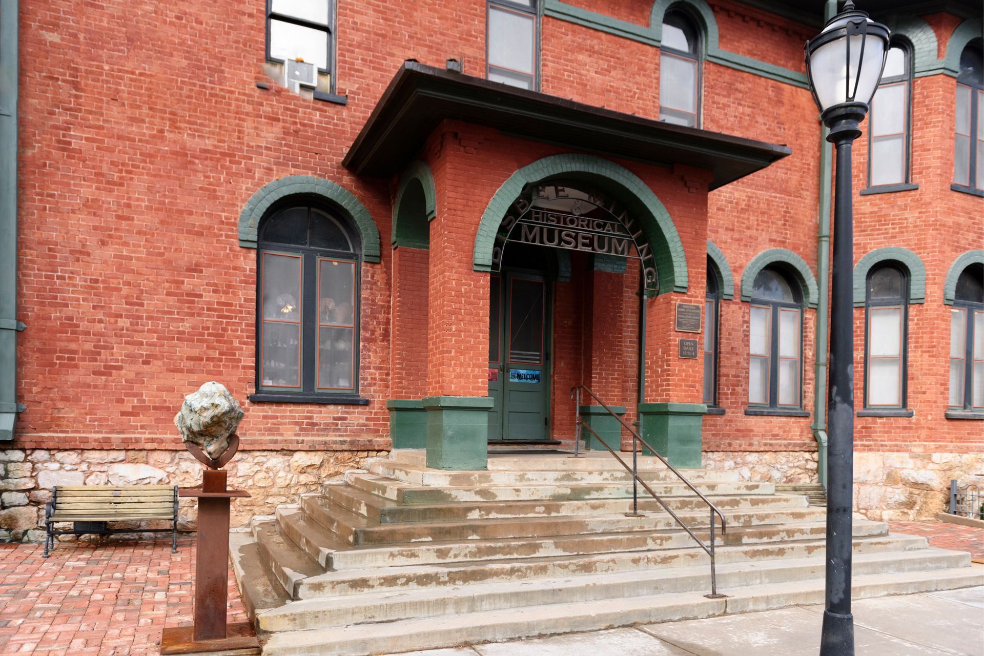 A Brick Building With Stairs and a Lamp Post in Front of It