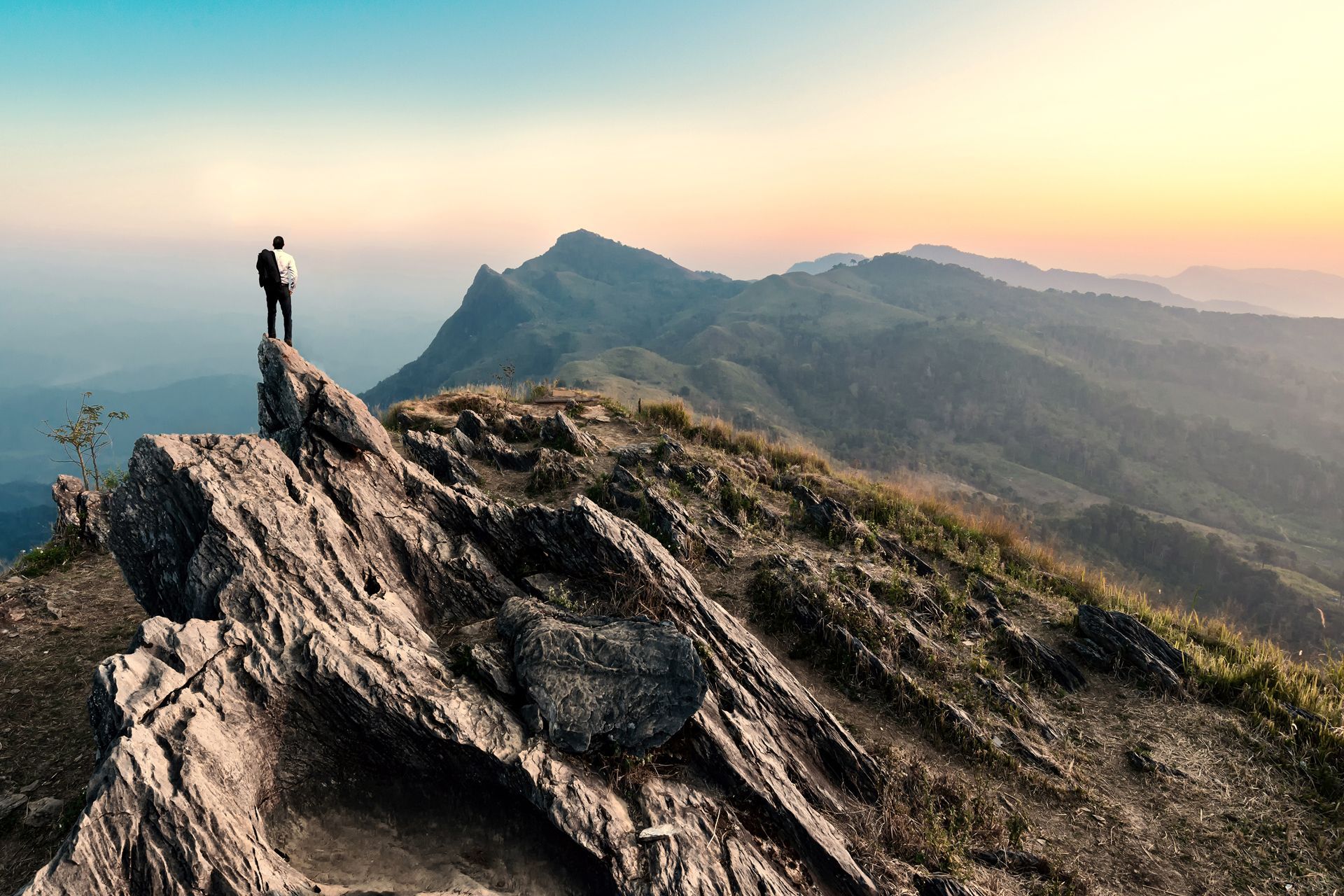 A Man is Standing on Top of a Rocky Mountain