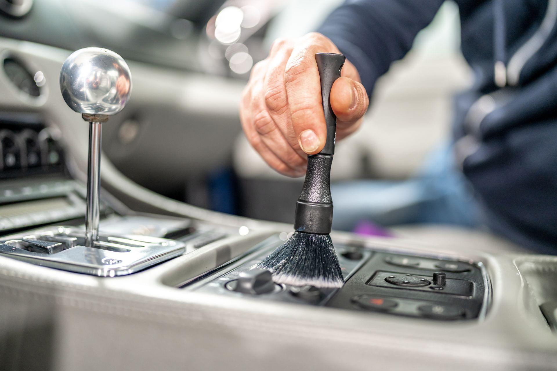 A person is cleaning the dashboard of a car with a brush.