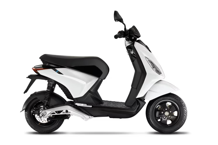 Uno scooter nero è parcheggiato su uno sfondo bianco.