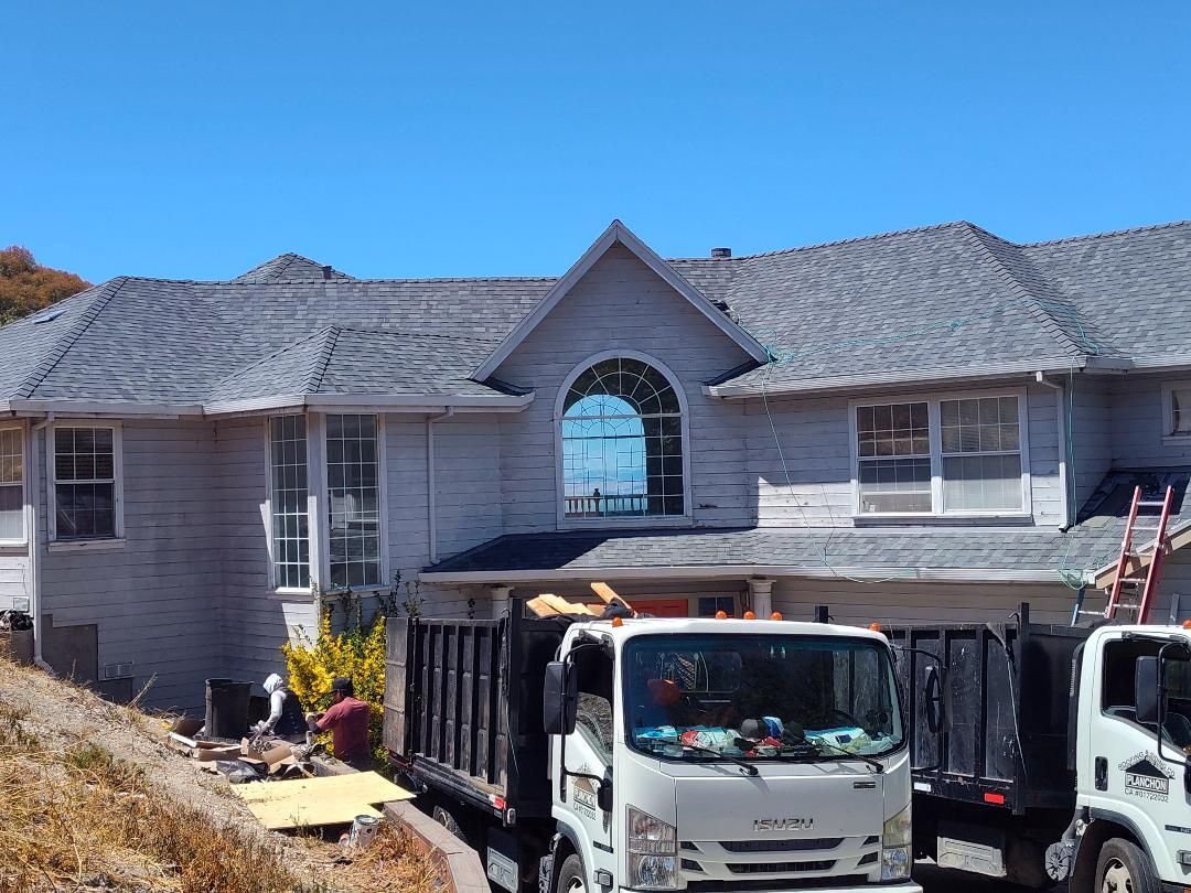 View of a large, corrugated metal roof on an industrial building under a partly cloudy sky. View of a large, corrugated metal roof on an industrial building under a partly cloudy sky.