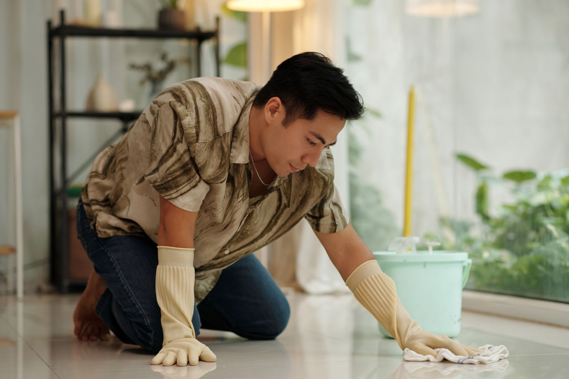 A woman is mopping the floor in a living room filled with boxes.