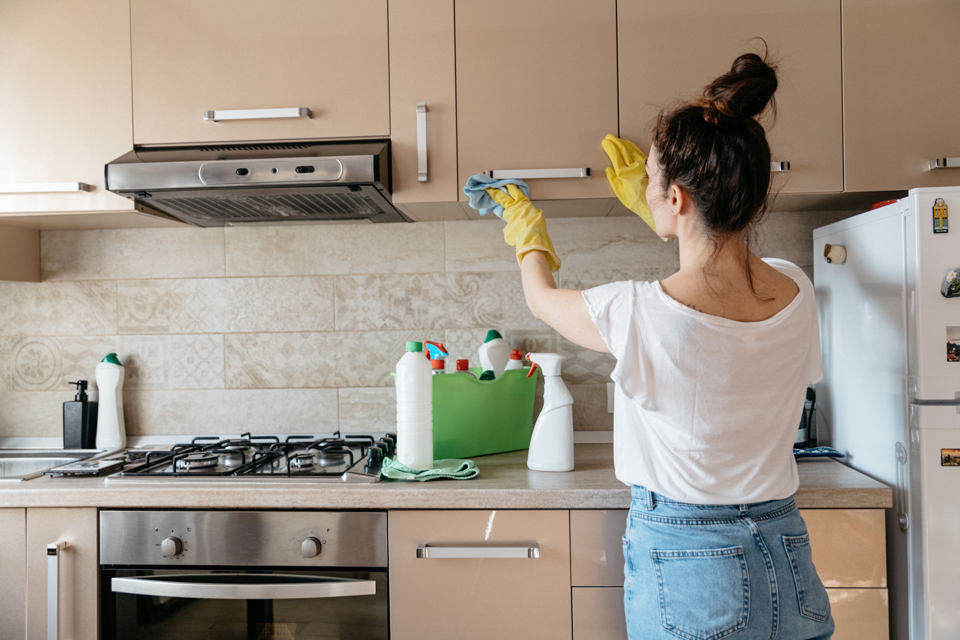 A woman is mopping the floor in a living room filled with boxes.