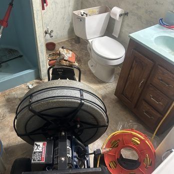 A toilet and sink in a bathroom with a drain cleaner, likely used to unclog a drain.