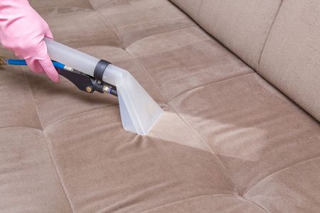 A Person Is Cleaning A Couch With A Water Extraction Machine — Big Red Carpet & Property Maintenance In Bowen, QLD