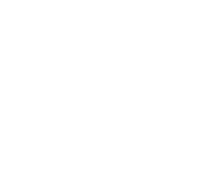 A person wearing an olive-green shirt and white apron uses a large knife to slice a baguette on a wooden cutting board.