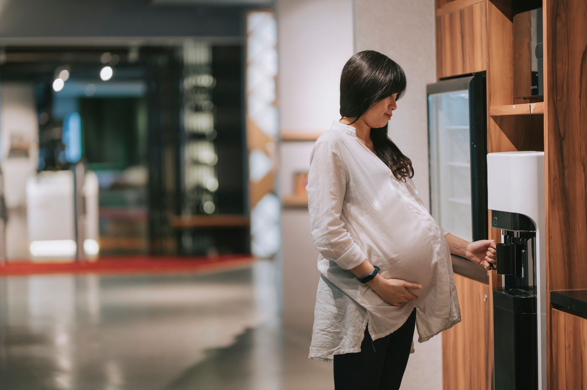 Person pouring yellow liquid from a beverage dispenser into a yellow cup.