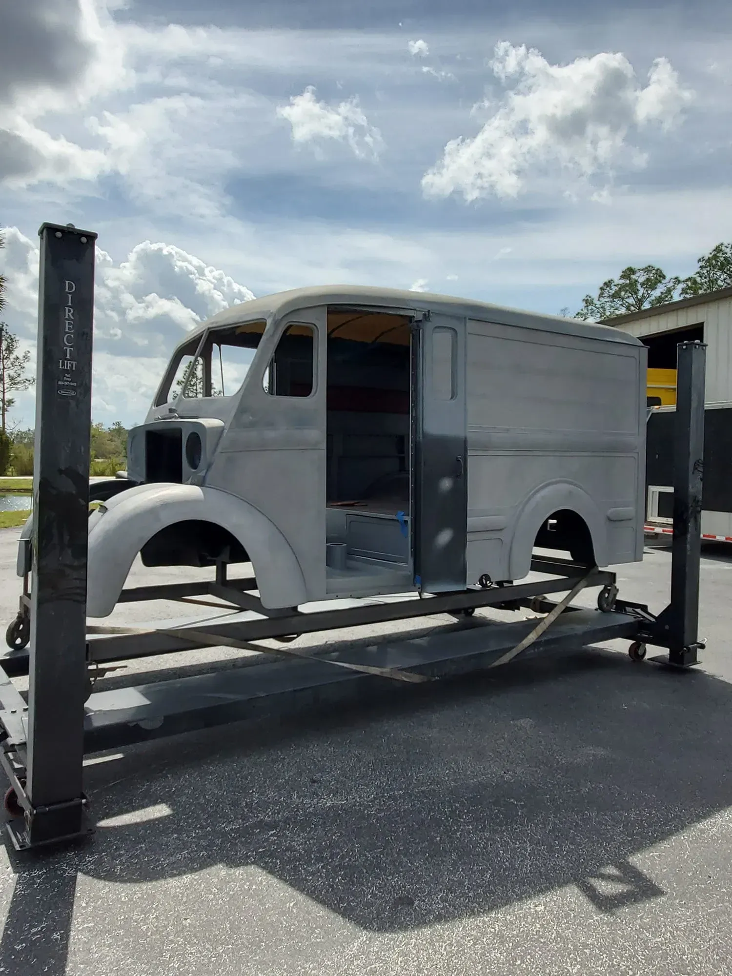 A white van is sitting on a lift in a parking lot.