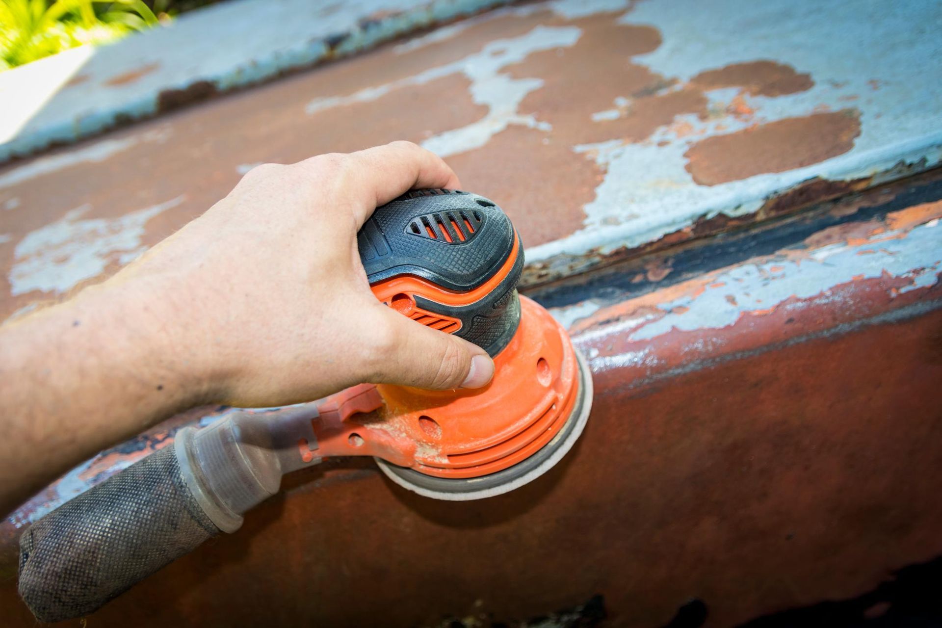 A person is sanding a boat with a sander.