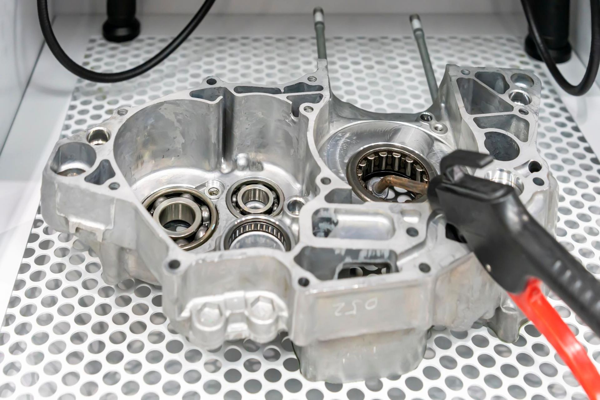 A close up of a motorcycle engine with a pair of pliers.