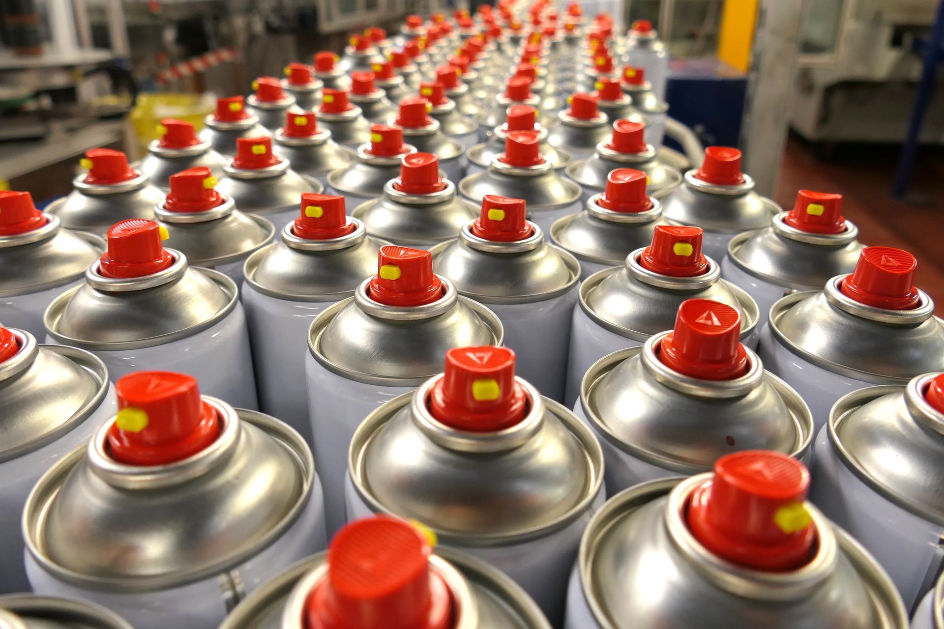 A row of spray cans with red caps in a factory