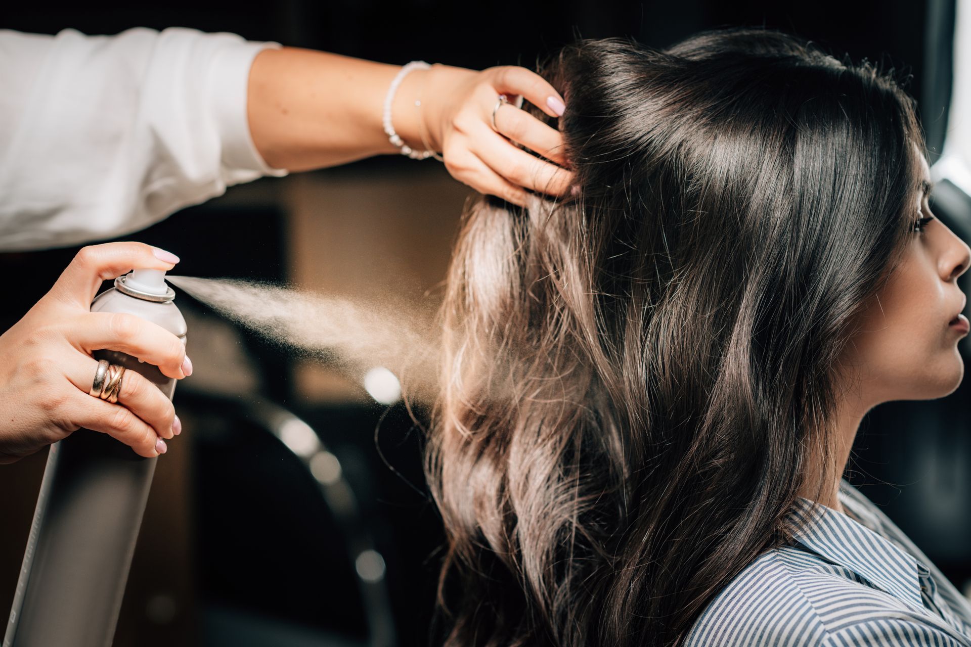 A woman is getting her hair sprayed by a hairdresser.