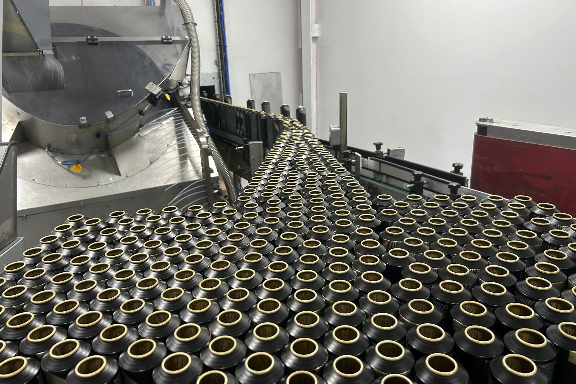 A conveyor belt filled with lots of black containers in a factory.