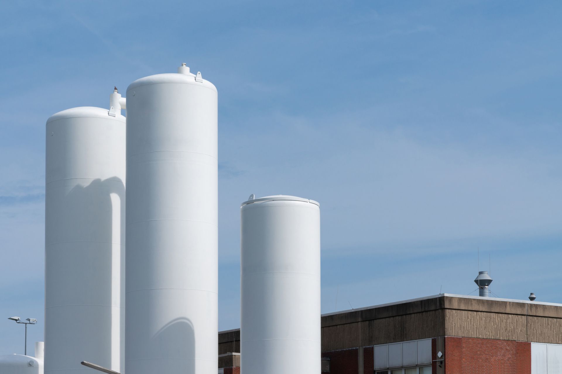 Three white tanks are sitting next to each other in front of a building.