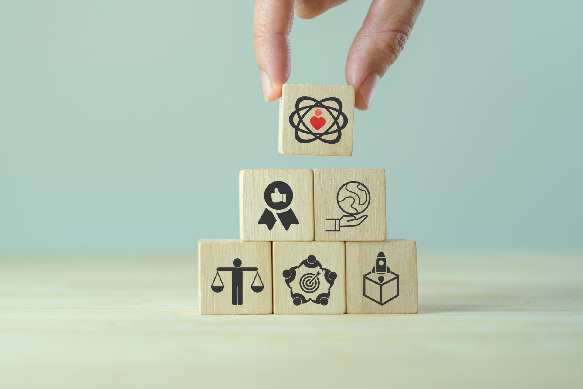 A person is stacking wooden blocks with icons on them.