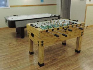 A foosball table is sitting next to a pool table in a game room.