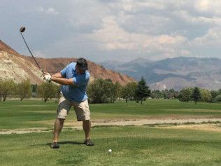 A man is swinging a golf club on a golf course.