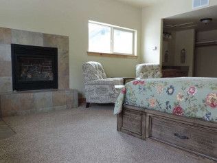 A bedroom with a bed , chair , fireplace and window.