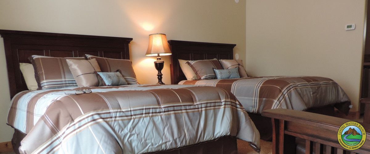 A bedroom with two beds and two lamps.