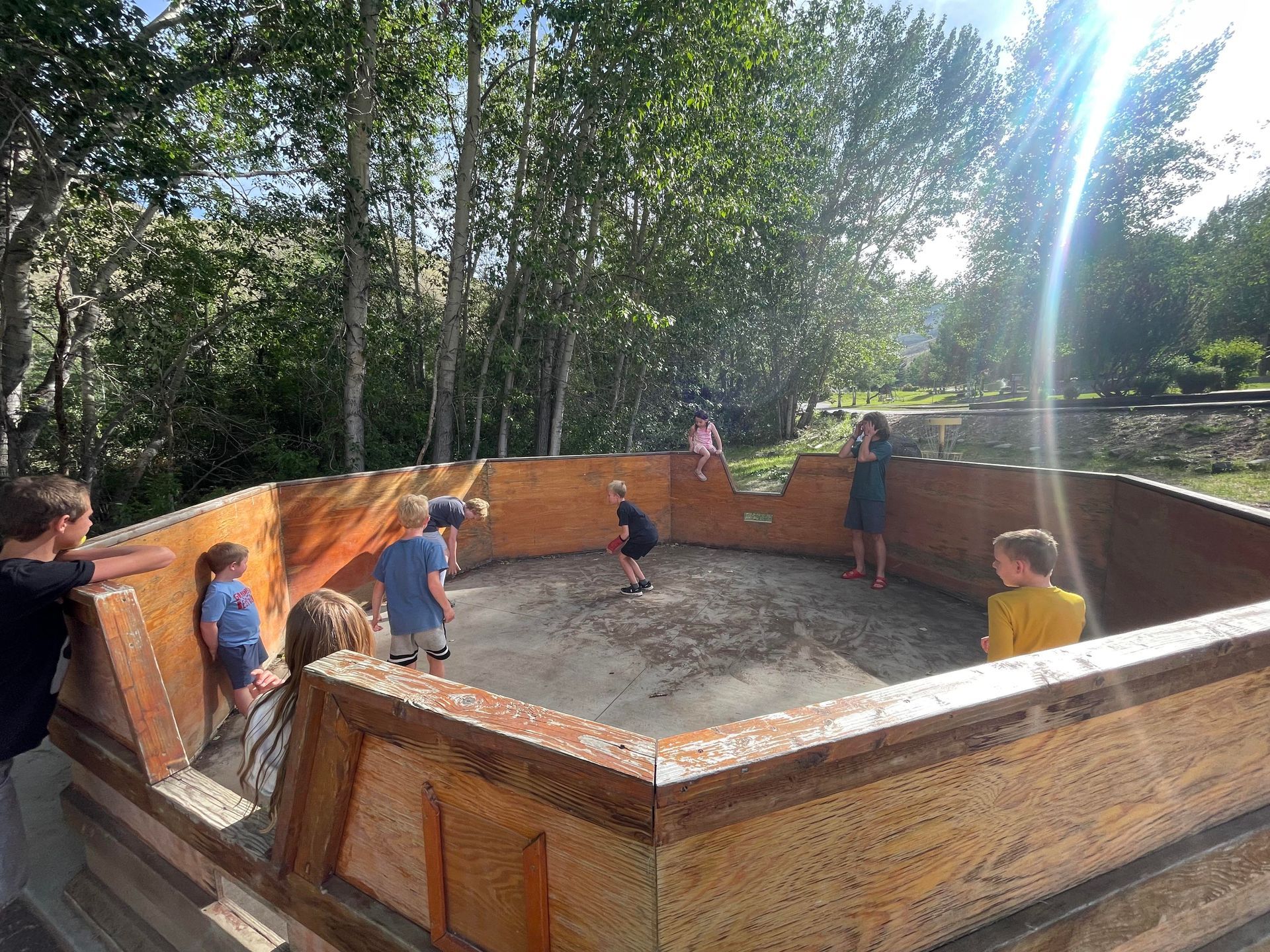 A group of children are playing a game of soccer on a wooden field.
