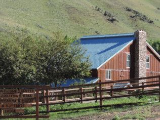 A house with a blue roof is behind a wooden fence