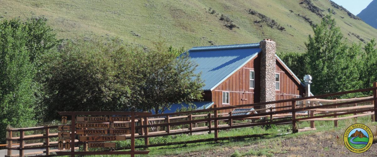 A red house with a blue roof is behind a wooden fence.