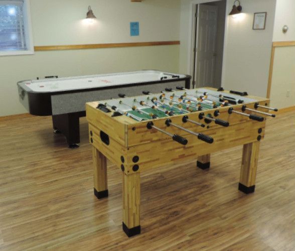 A foosball table in a game room next to a pool table