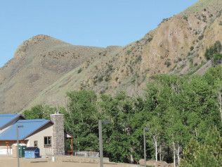 A house with a blue roof is surrounded by trees and mountains.