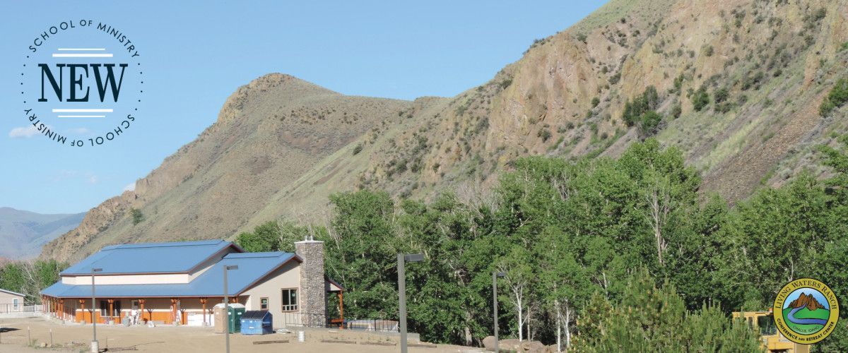 A house with a blue roof is surrounded by trees and mountains.